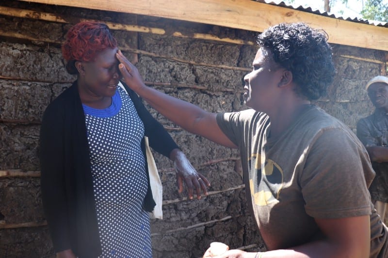 Elizabeth Kamboy applies her handmade lotion to Village Enterprise Field Associate Carolyne Wafula’s face.