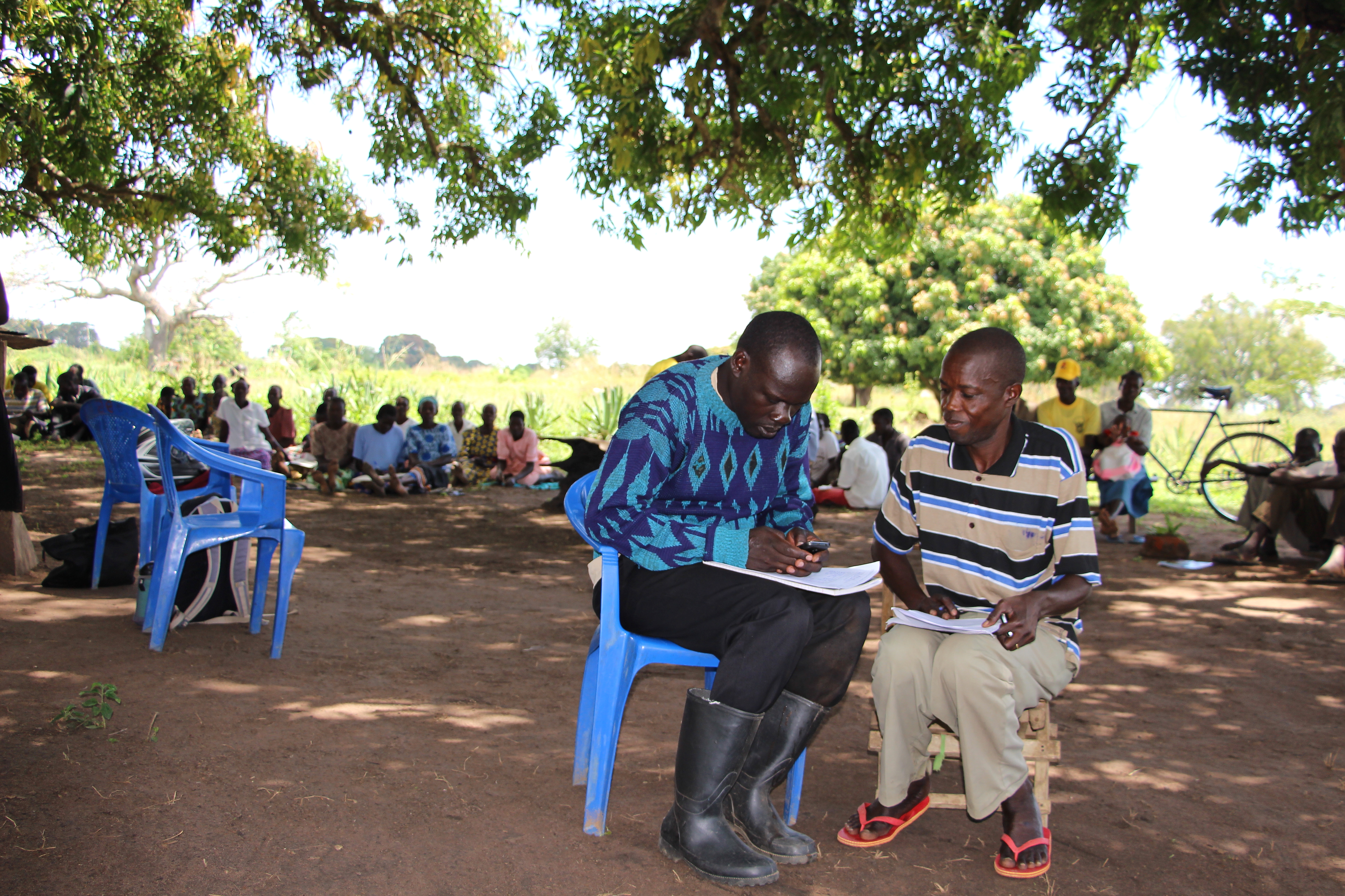 Village Enterprise Field Coordinator Maurice Eriaku works with a Business Owner to complete the Small Business Survey.