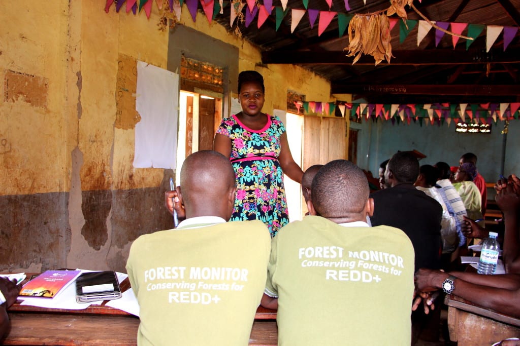 Village Enterprise Business Mentor Evelyne Kusiima poses a savings related question to Forest Monitors.